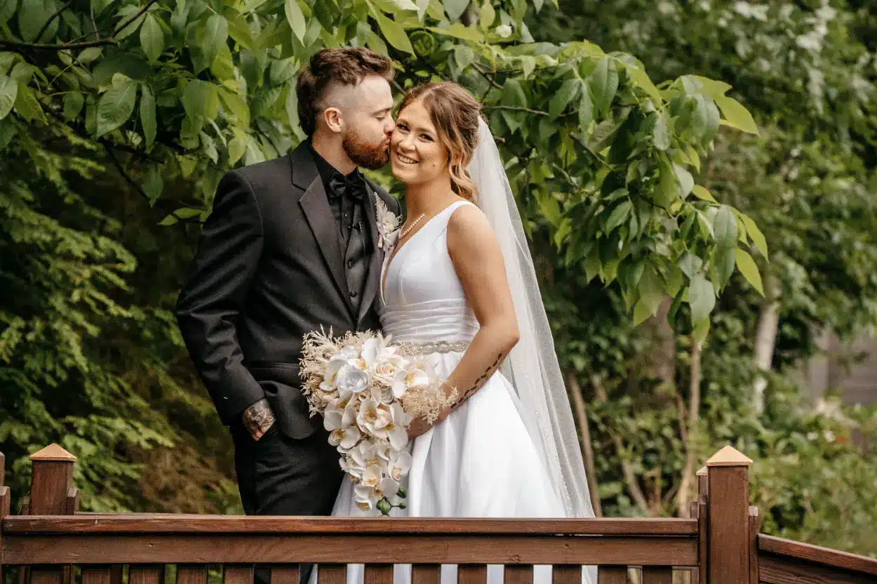Groom kiss bride on cheek