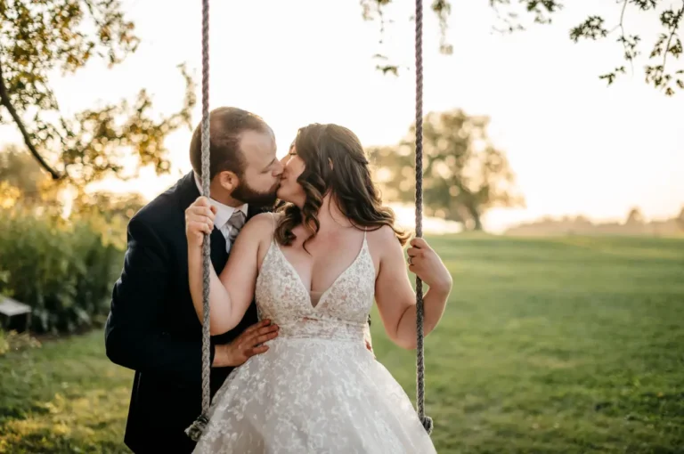 Bride on swing kissing groom