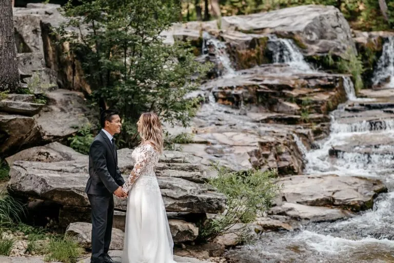 Bride and groom at a scenic outdoor wedding venue in New England with a natural waterfall backdrop