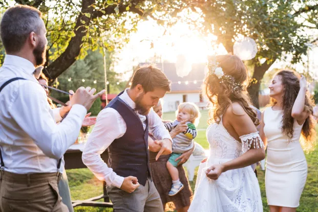 Guests dancing at an outdoor wedding reception at sunset