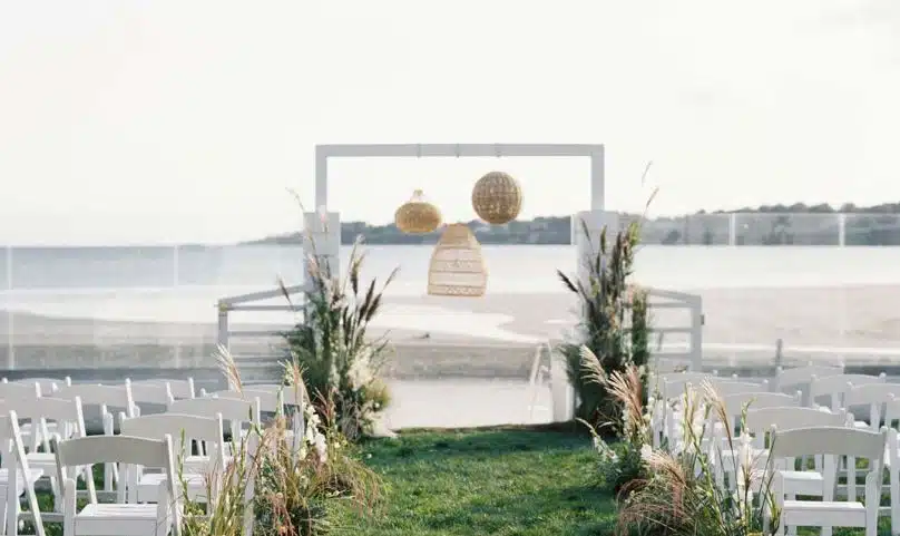 A beachside wedding ceremony setup at The Newport Beach House in Middletown, Rhode Island, with a modern arch and ocean view.