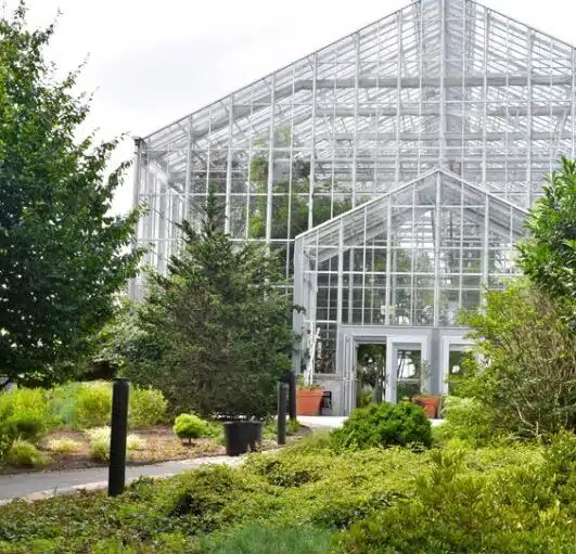 The glass exterior of the Roger Williams Park Botanical Center in Providence, Rhode Island, surrounded by lush green gardens.