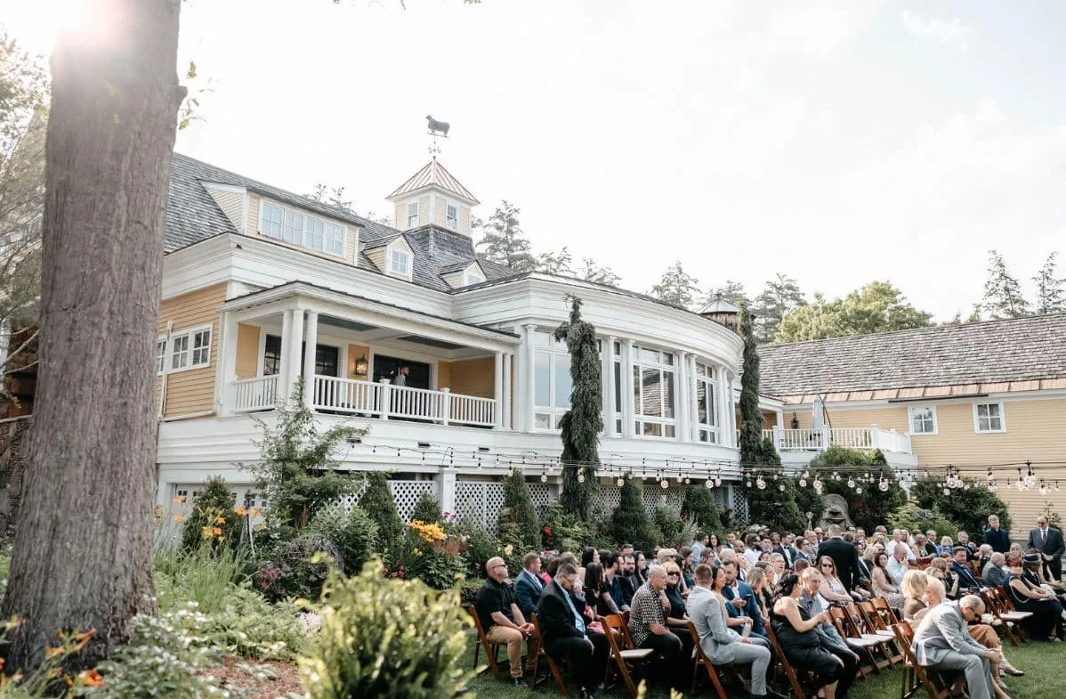 An outdoor wedding ceremony on the lawn at The Bedford Village Inn in Bedford, New Hampshire, with guests seated.
