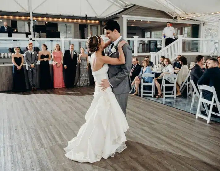 A bride and groom share their first dance at The Popponesset Inn in Mashpee, MA, surrounded by guests and the wedding party.