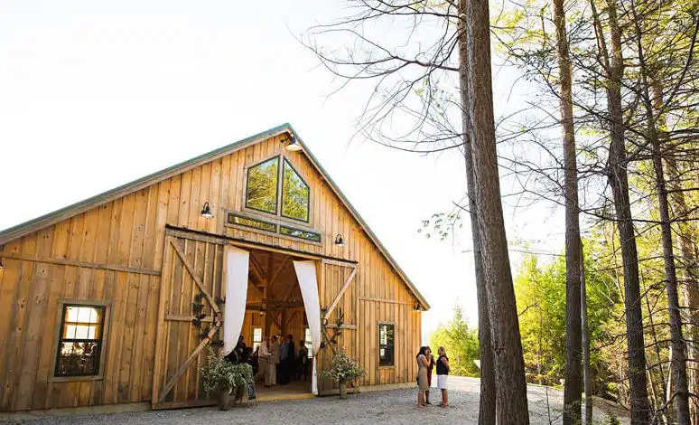 The exterior of the large wooden barn at Granite Ridge Estate and Barn in Norway, Maine, with guests by the entrance.