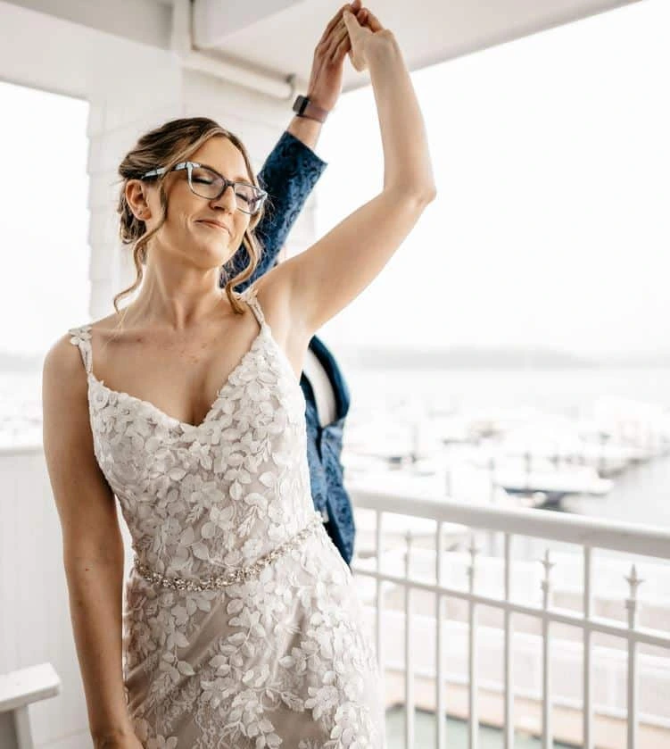 A bride with glasses is twirled by her groom on a balcony overlooking the water at Great Island Common in New Castle, New Hampshire.