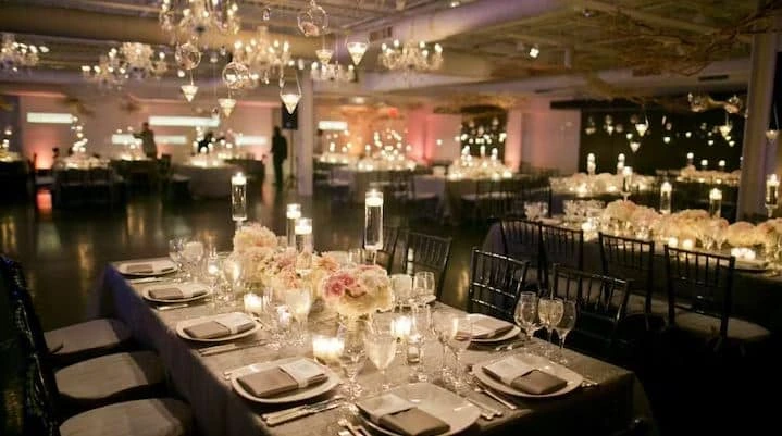An elegant wedding reception at The Loading Dock in Stamford, Connecticut, with long tables, candles, and hanging lights.