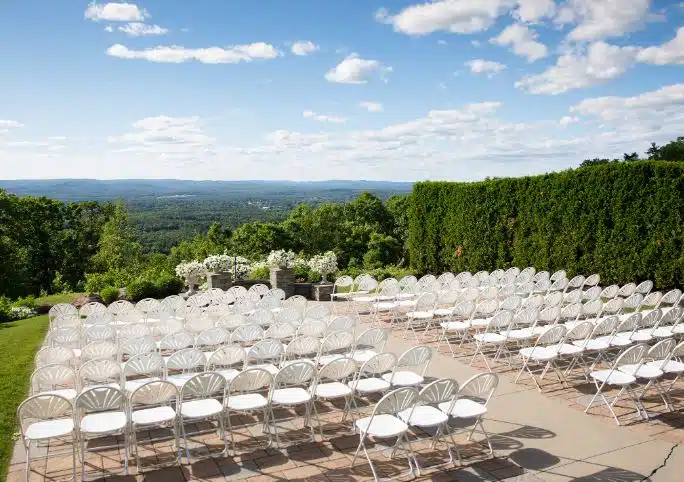 An outdoor wedding ceremony setup at The Log Cabin in Holyoke, Massachusetts, with a scenic mountain view in the background.