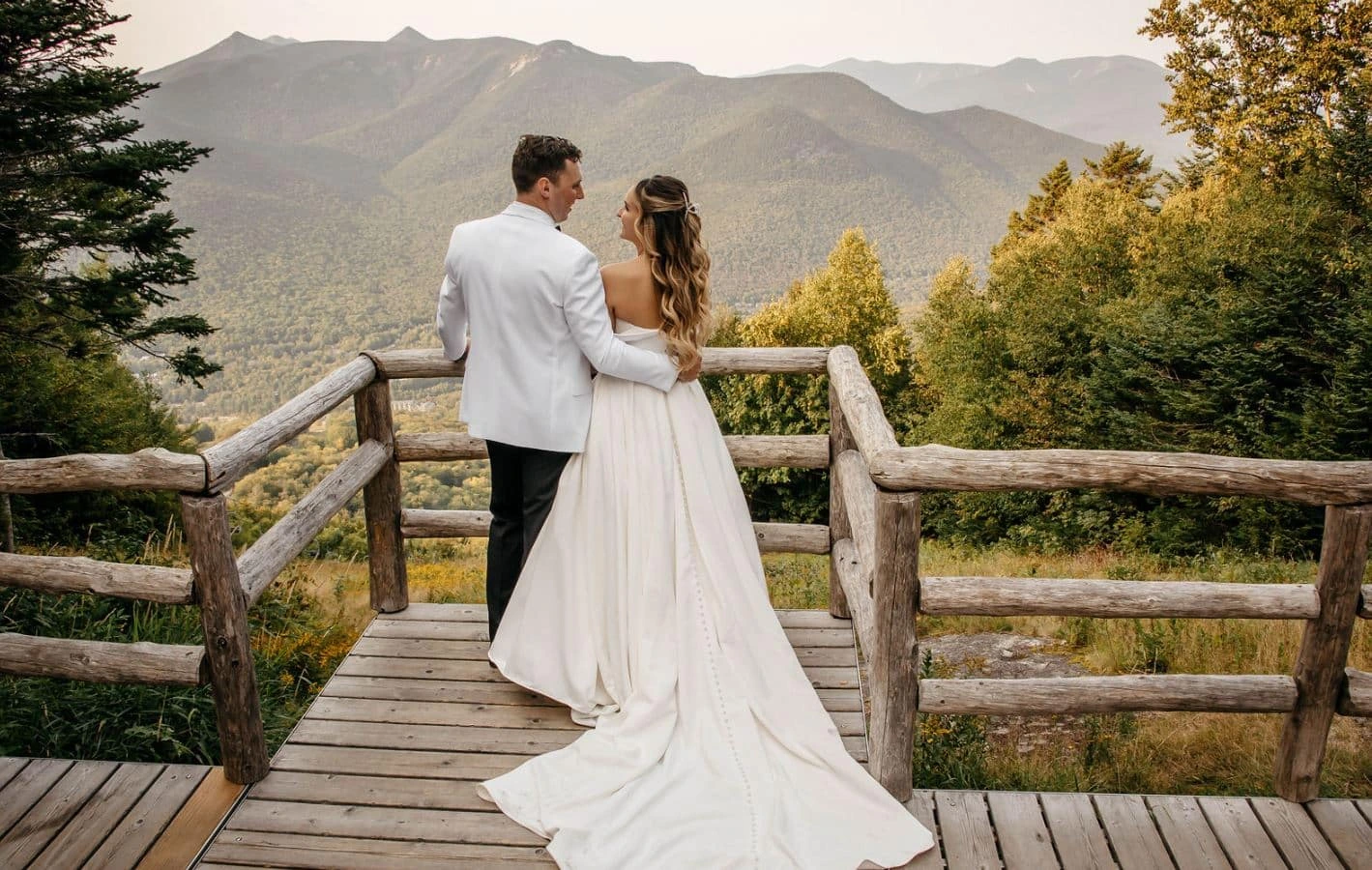 A bride and groom look out at the mountain view from an observation deck at Loon Mountain Resort in Lincoln, New Hampshire.