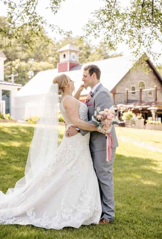A bride and groom share a tender moment on the lawn of the Oscar Barn Wedding Venue in Hooksett, New Hampshire.