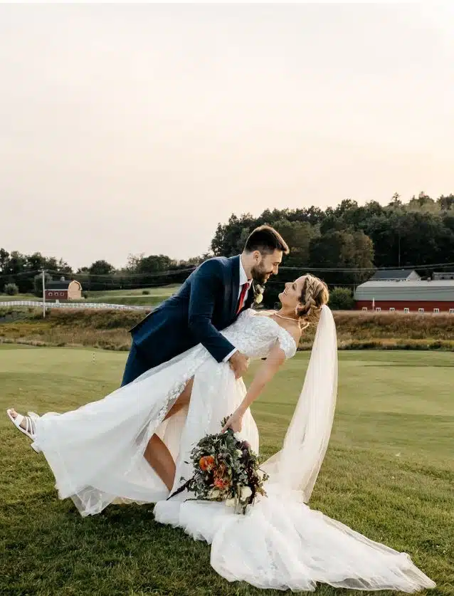A groom dips his bride on the golf course during their wedding at The Red Barn at Outlook Farm in South Berwick, Maine.