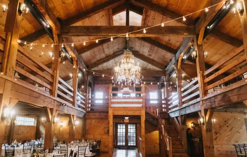 The rustic barn reception hall at The Red Lion Inn in Stockbridge, Massachusetts, with a grand chandelier and string lights.