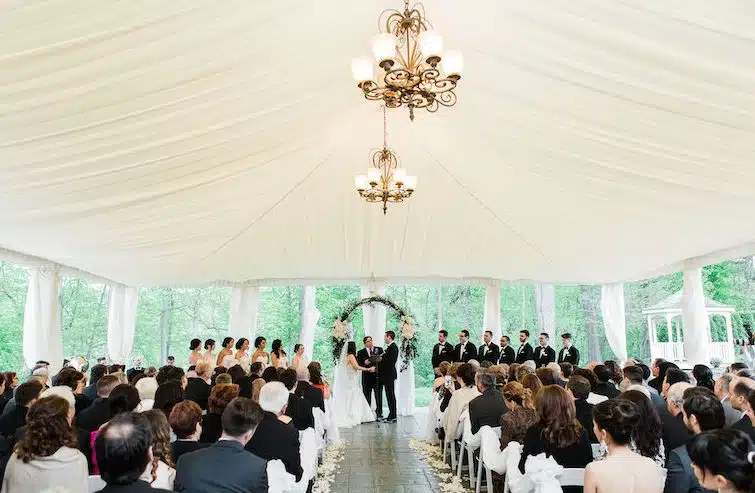A wedding ceremony under a tent at The Riverview in Weatogue, Simsbury, CT, with guests watching the couple at the altar.
