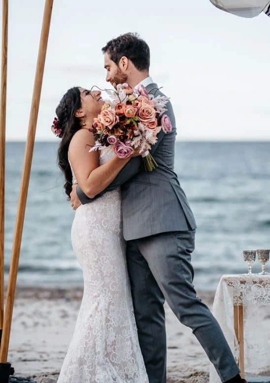 A bride and groom embrace during their wedding ceremony on Sandy Neck Beach in West Barnstable, Massachusetts.