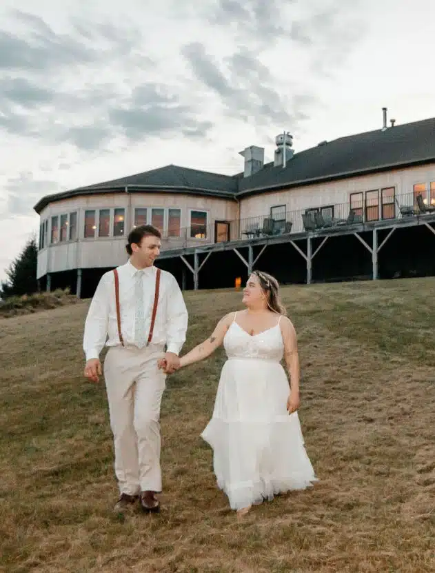 A bride and groom hold hands and walk across the lawn at Spring Hill, a wedding venue in South Berwick, Maine.