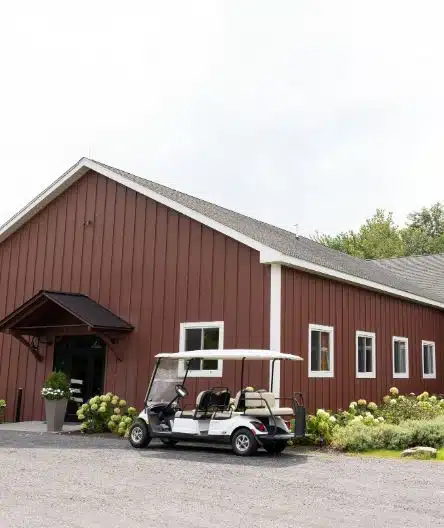 The exterior of the red wedding barn at The BARN at Liberty Farms in Ghent, NY, with a golf cart parked outside.