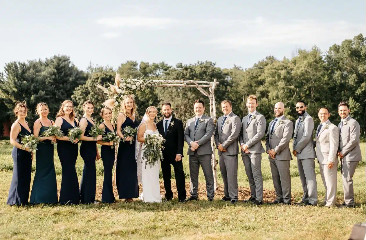 A bride, groom, and their wedding party pose for a photo in a field at Ross Hollow Farm in Connecticut.