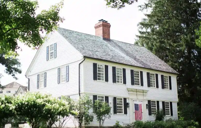 The historic white farmhouse at Winvian Farm Hotel in Morris, Connecticut, surrounded by lush green trees.