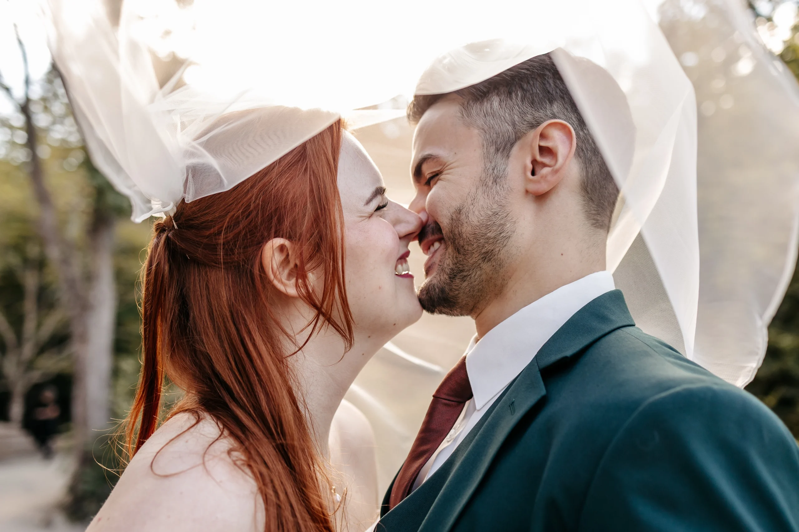 A joyful bride and groom laugh and touch noses under her veil during their wedding elopement in Acadia National Park.
