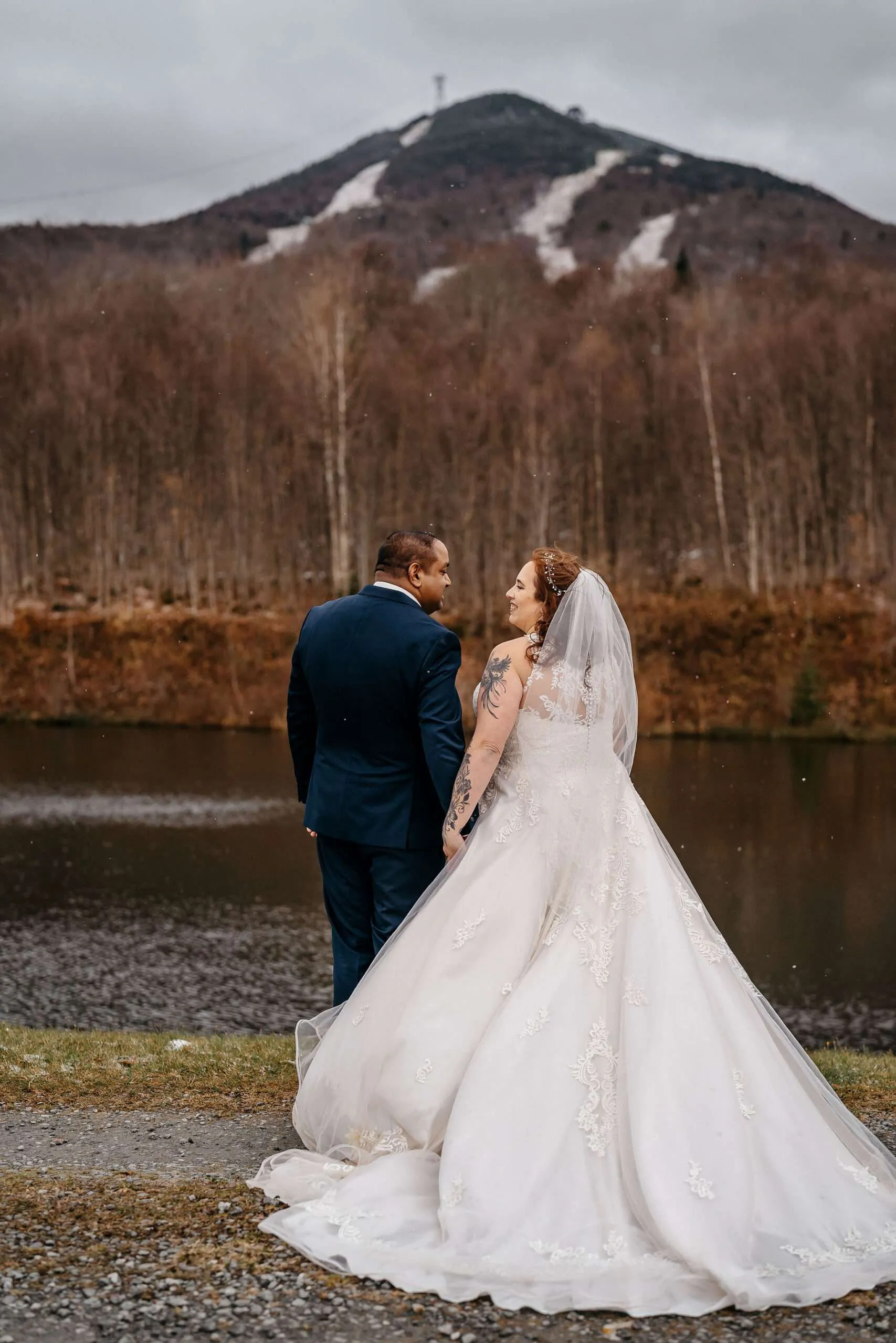 Couple by lake with mountain backdrop.