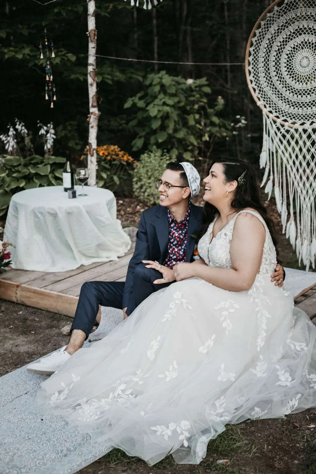 Joyful Jewish wedding portrait of the Chatan (groom in kippah) and Kallah (bride) sitting together and smiling.