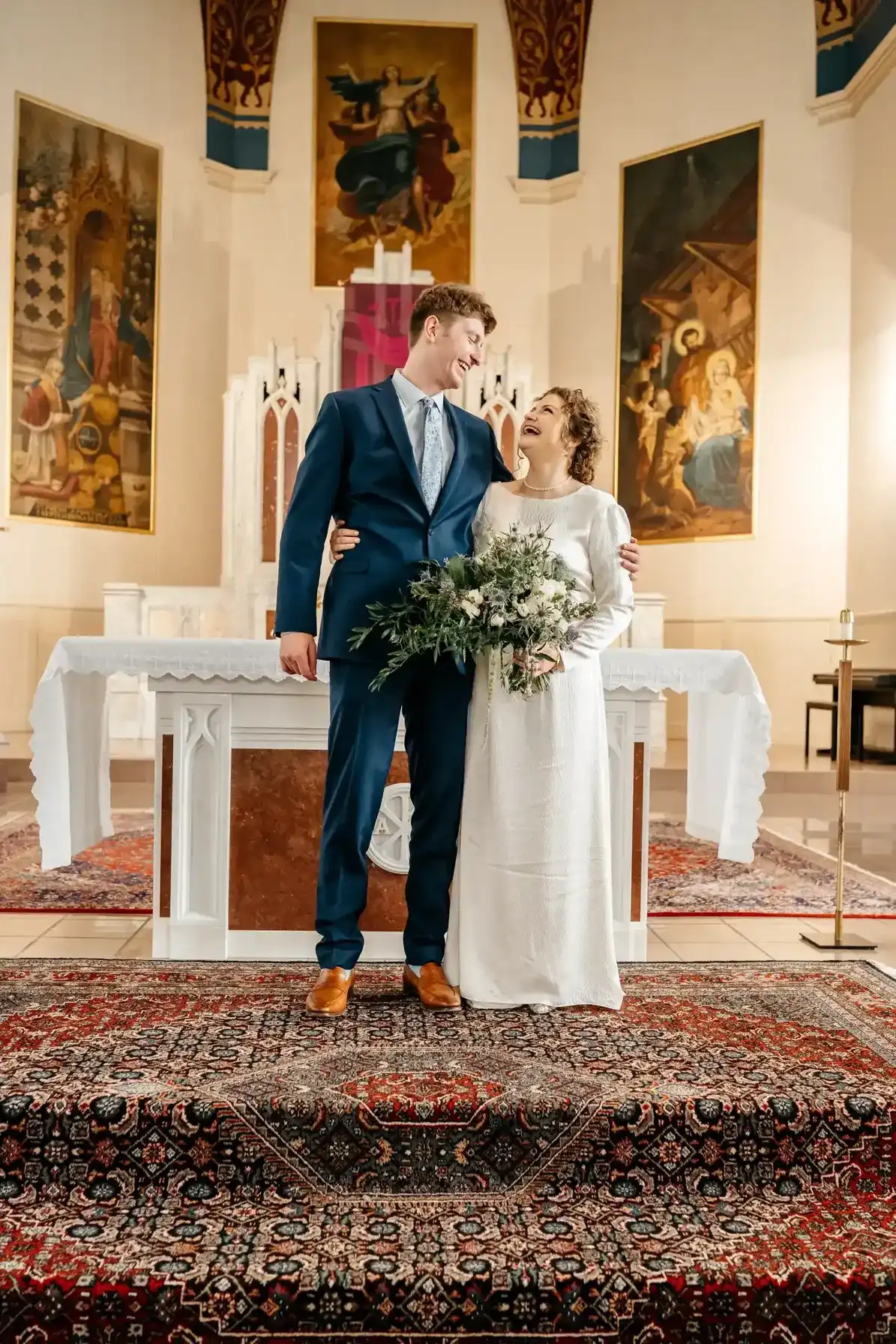 Joyful bride and groom laughing together at the altar inside Immaculate Heart of Mary Church in Rutland, VT.