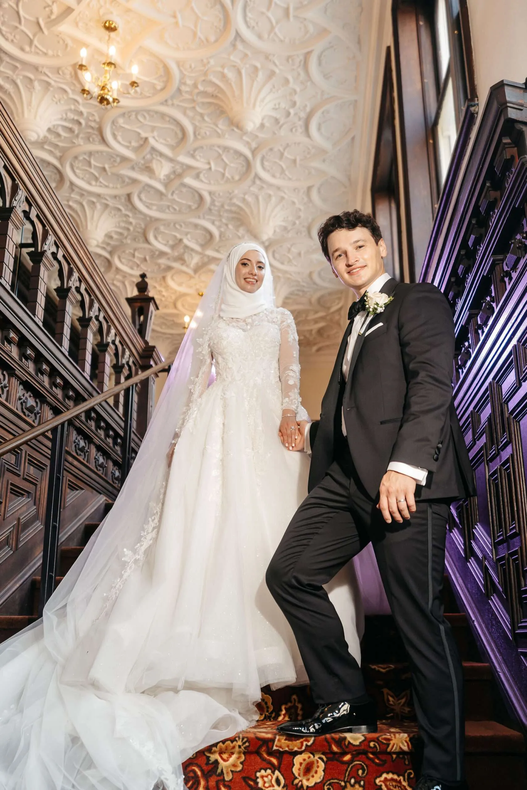 Soumaya and Patrick posing on the ornate grand staircase at The Branford House in Groton, Connecticut.