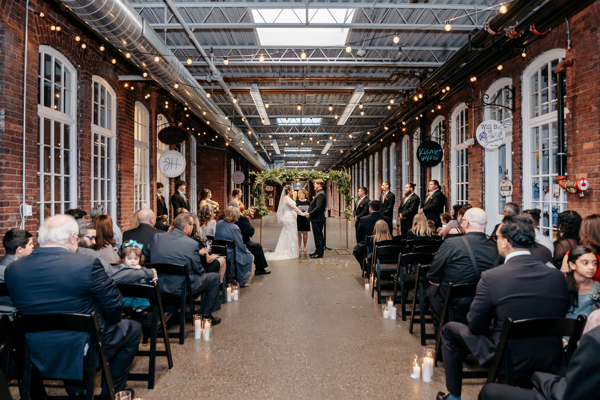 Wedding ceremony under string lights in an industrial brick venue