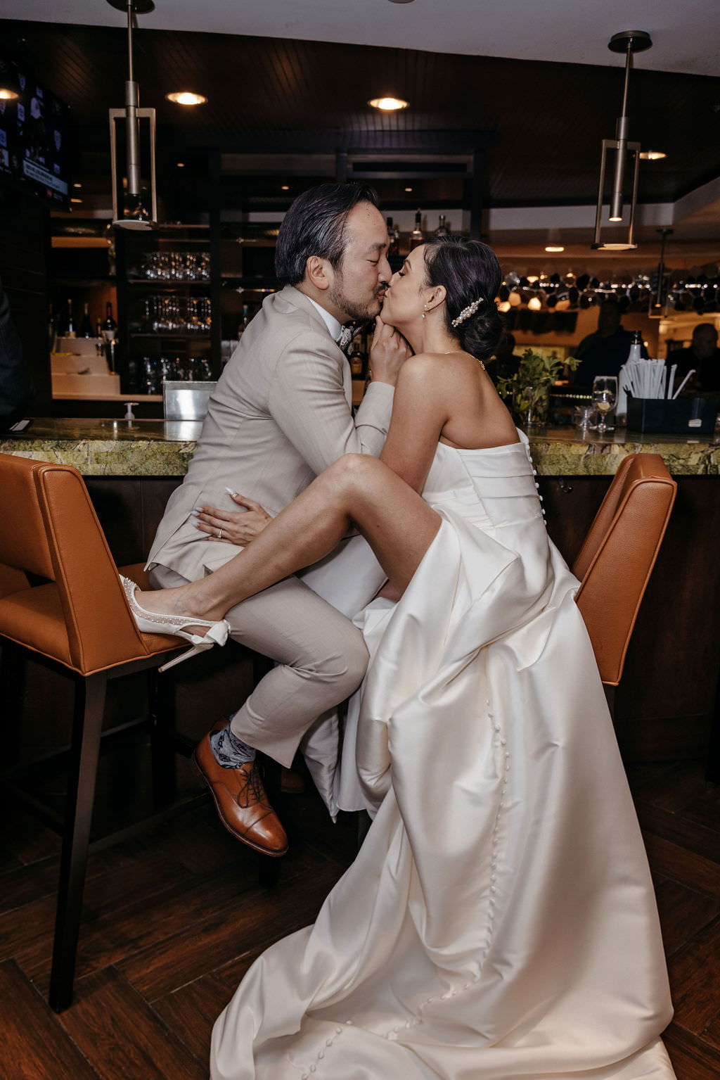 Bride and groom kissing on barstools at a hotel bar