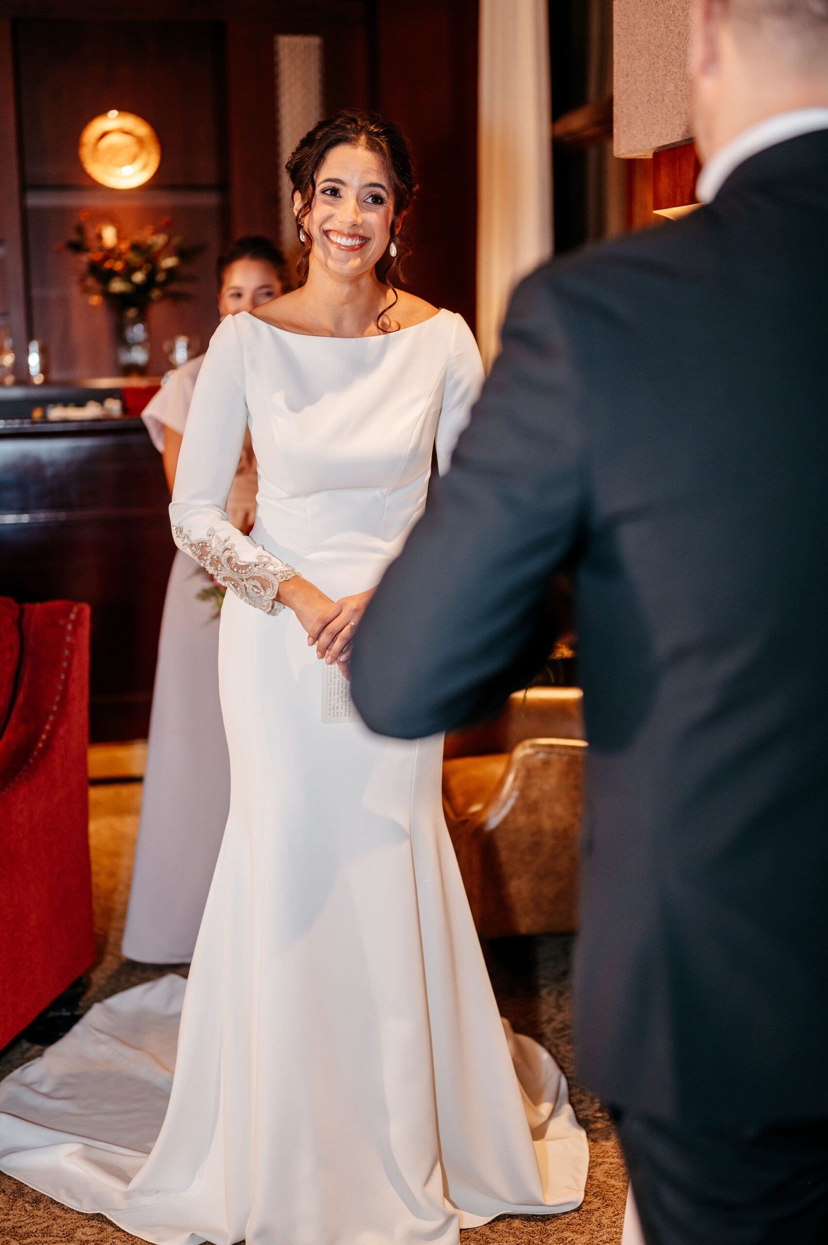 Bride smiling at her groom during an intimate ceremony in a wood-paneled room