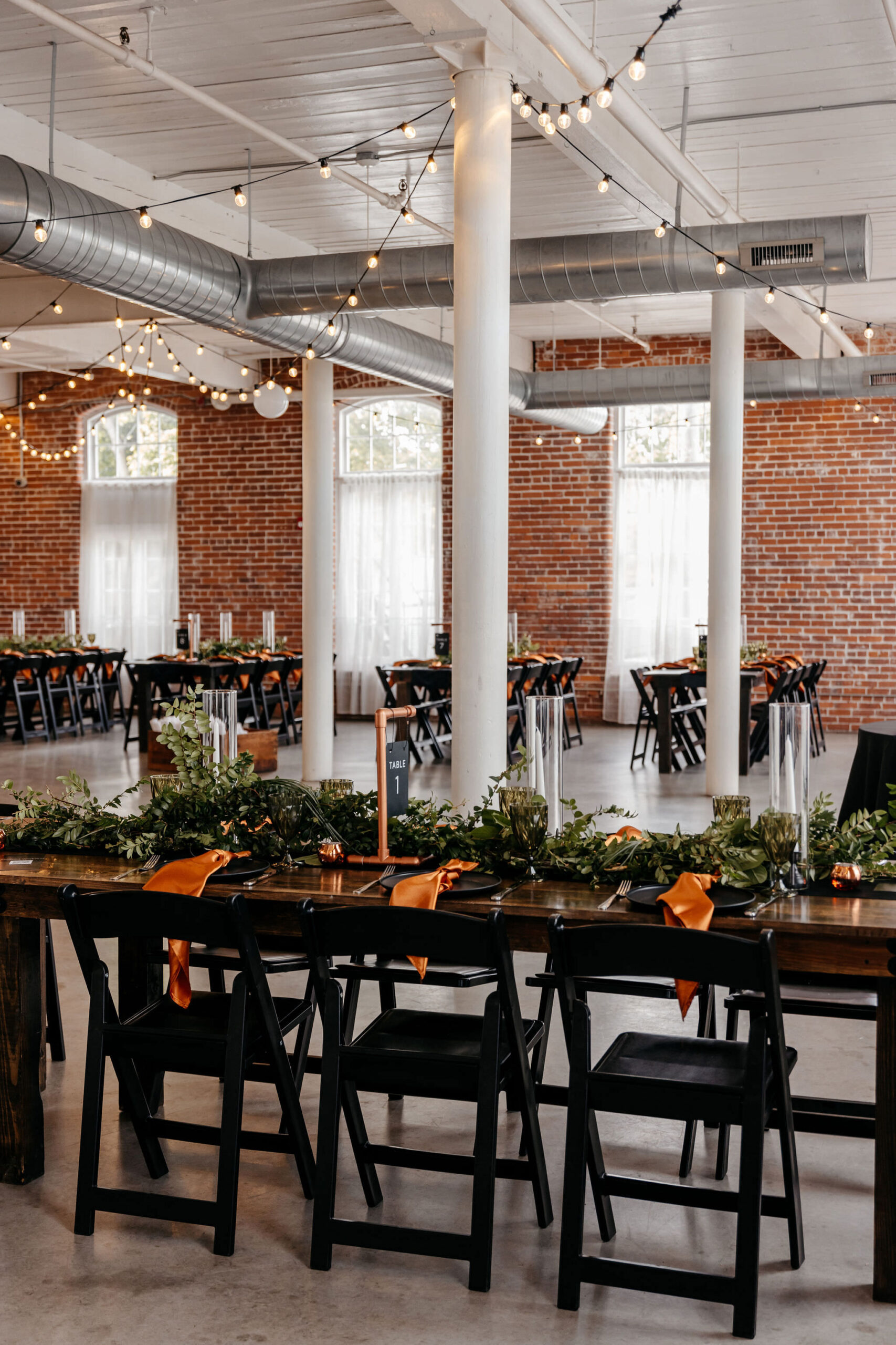 Industrial loft reception space with exposed brick, greenery and orange accents
