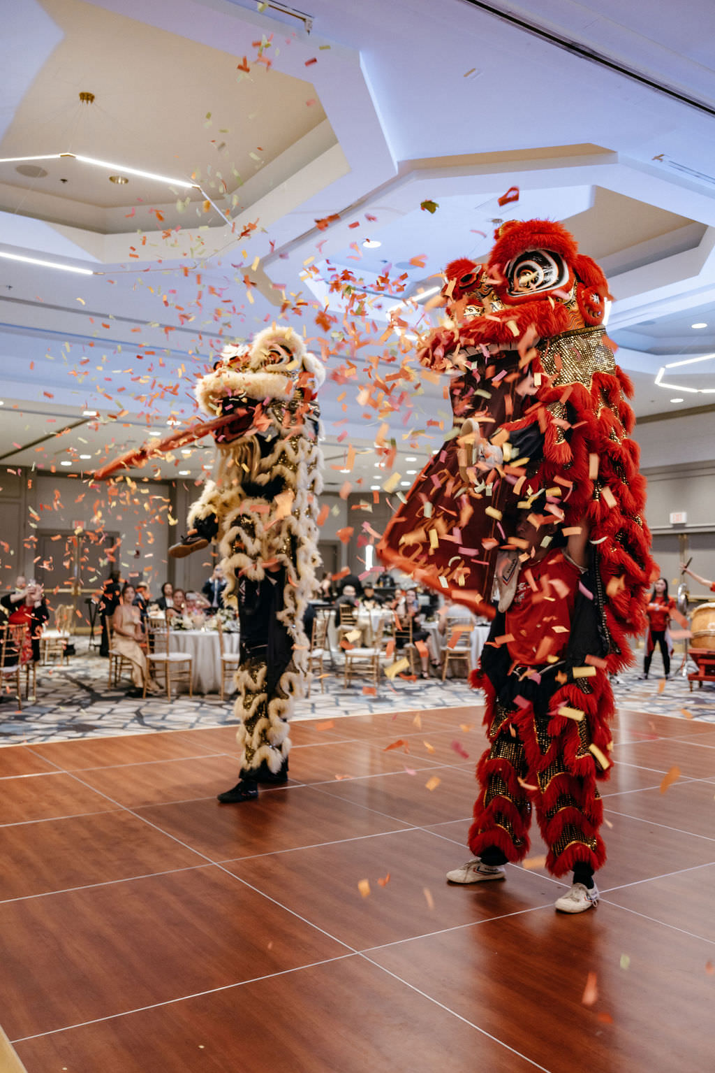 Lion dancers performing amid confetti at a Burlington Marriott wedding reception