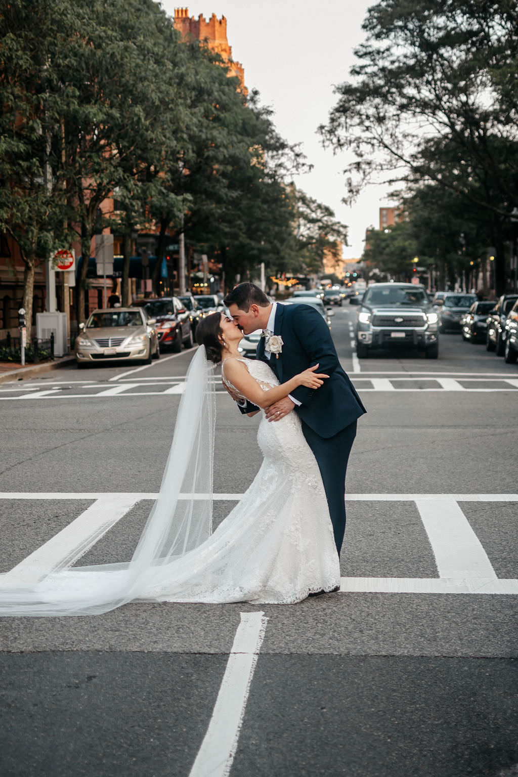 Groom dipping and kissing his bride in a crosswalk on a Boston street