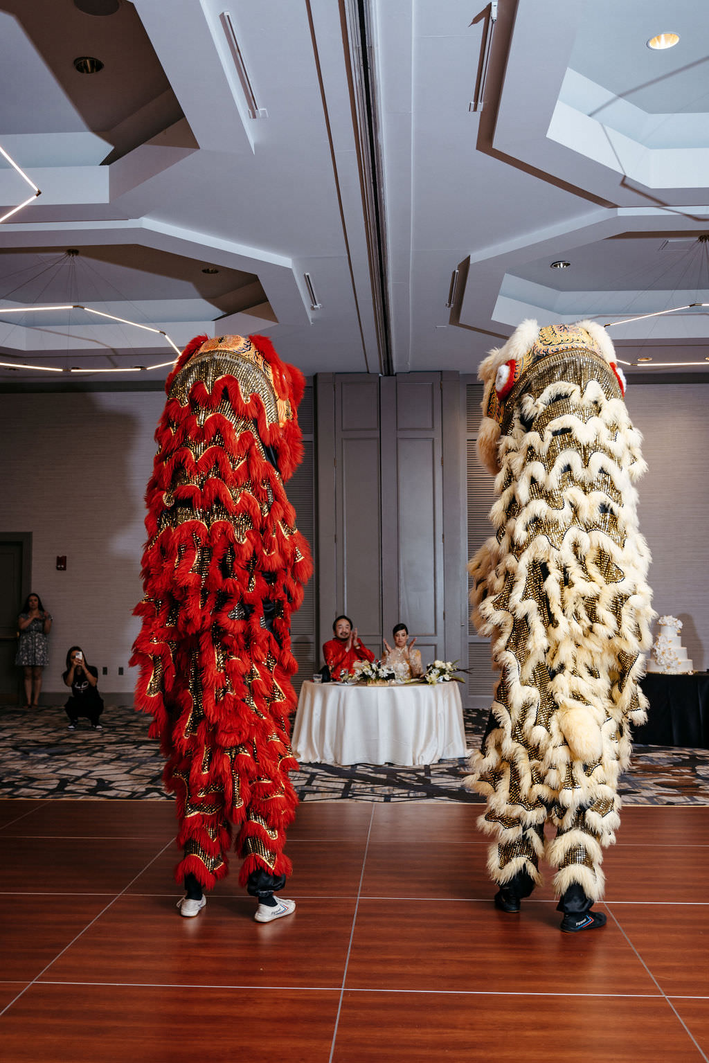 Two lion dancers performing in front of the couple's sweetheart table