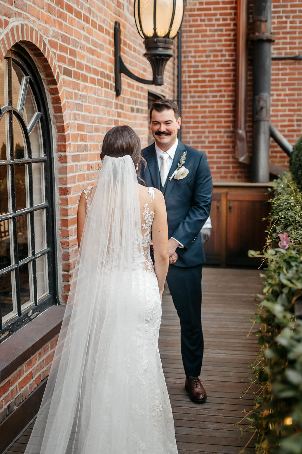 Groom smiling at his bride during a first look on a brick terrace downtown
