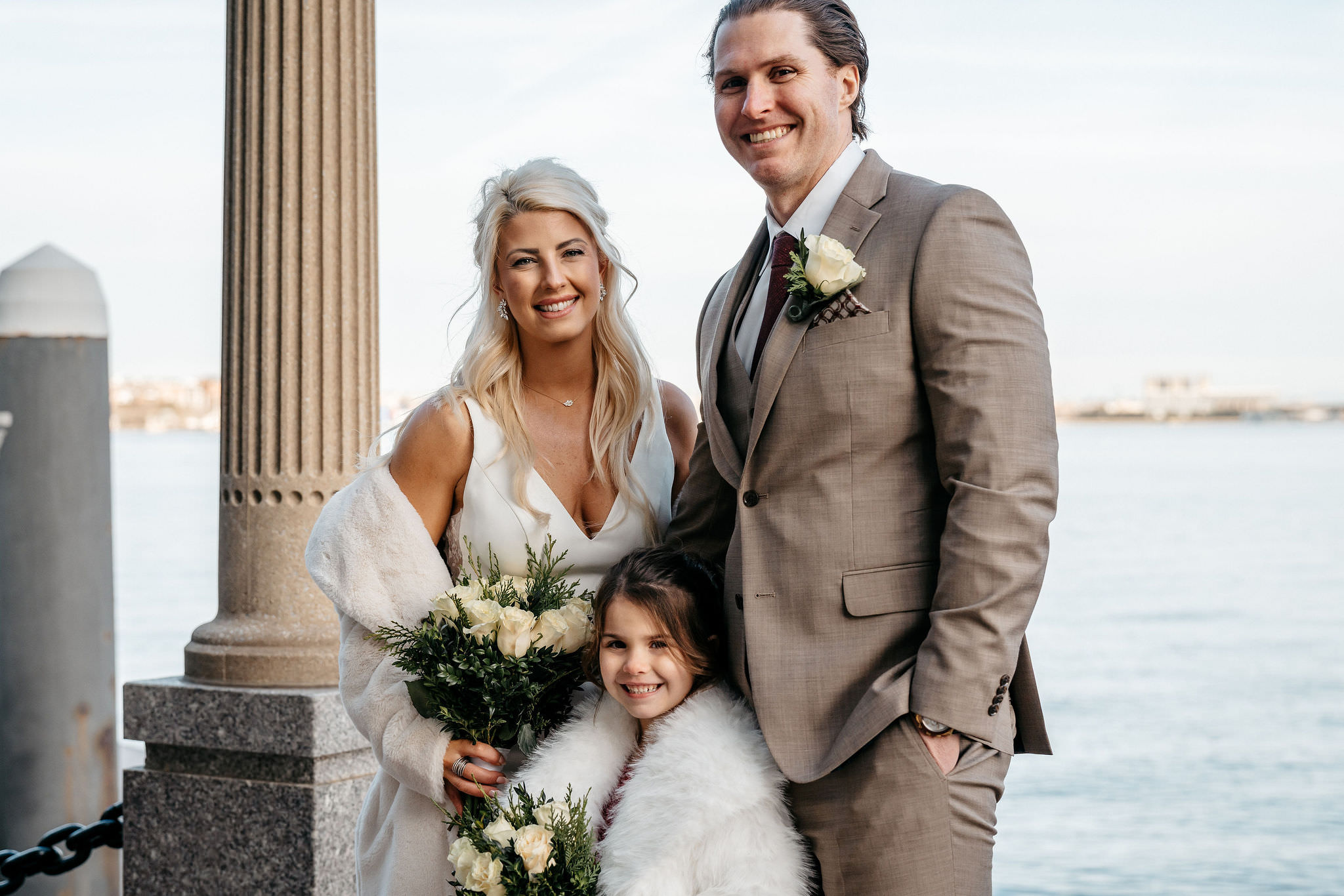 Winter bride in a fur wrap with her groom and flower girl on the Boston waterfront