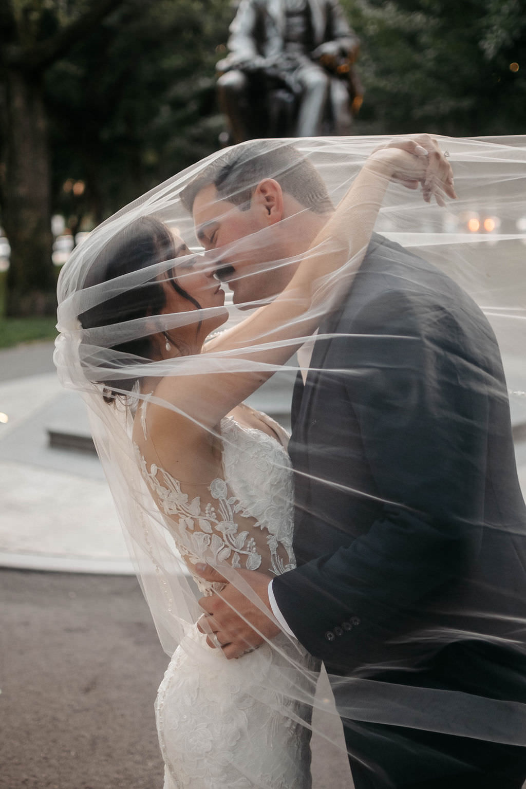 Couple kissing beneath the bride's sheer veil in a Boston park