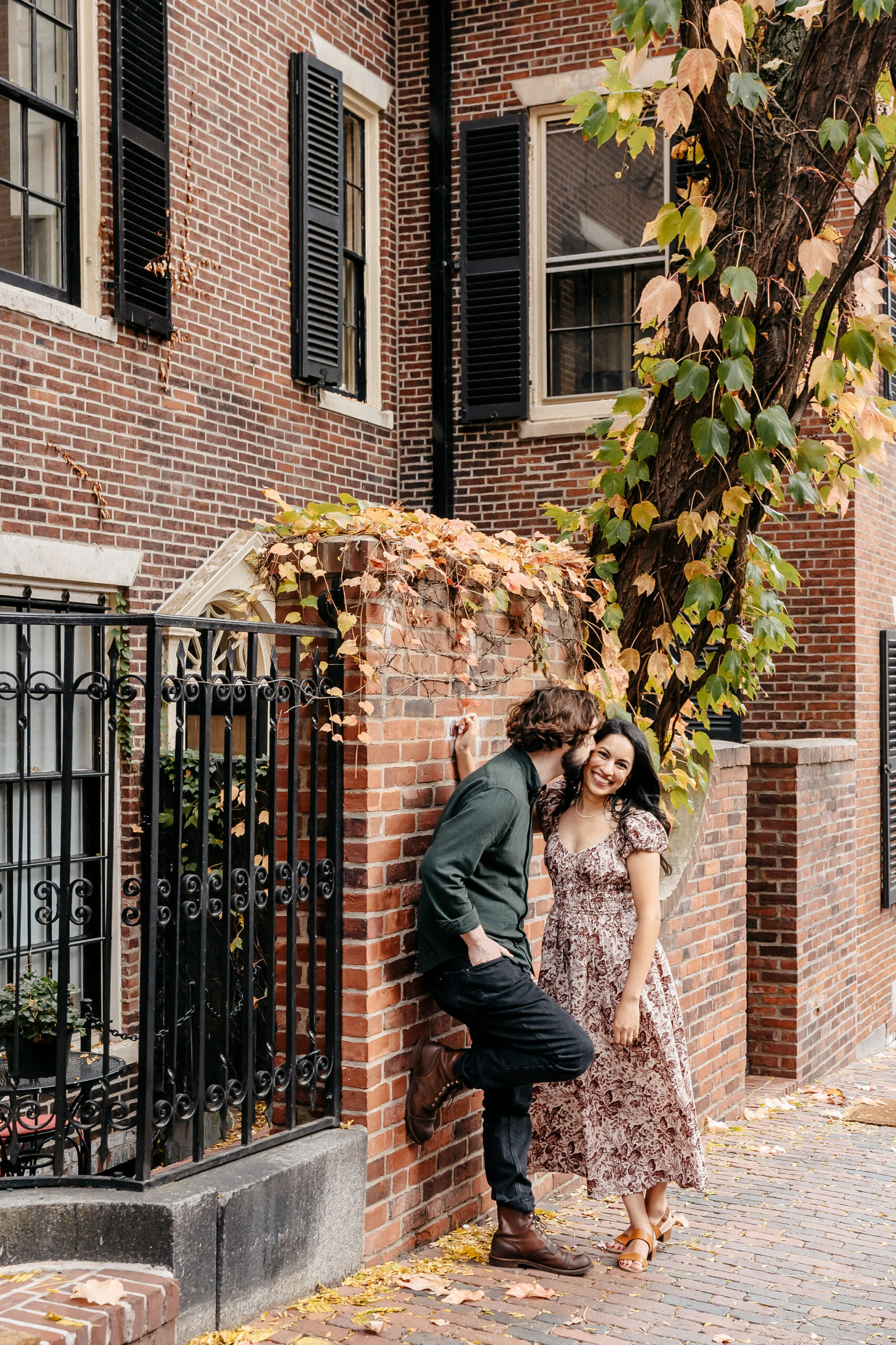 Couple laughing beside an ivy-covered brick wall on Beacon Hill in autumn