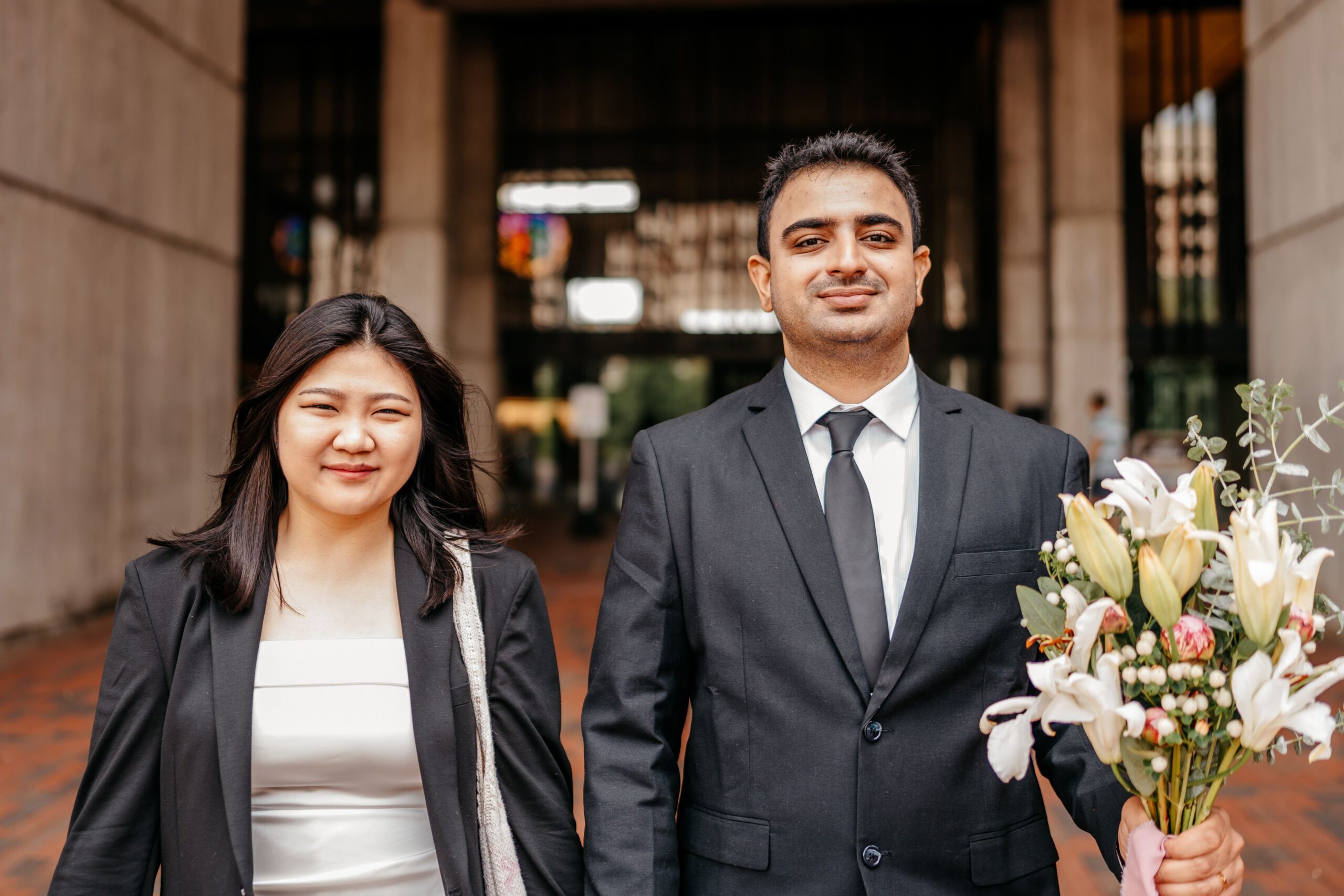 Newlyweds with a lily bouquet outside Boston City Hall after their ceremony