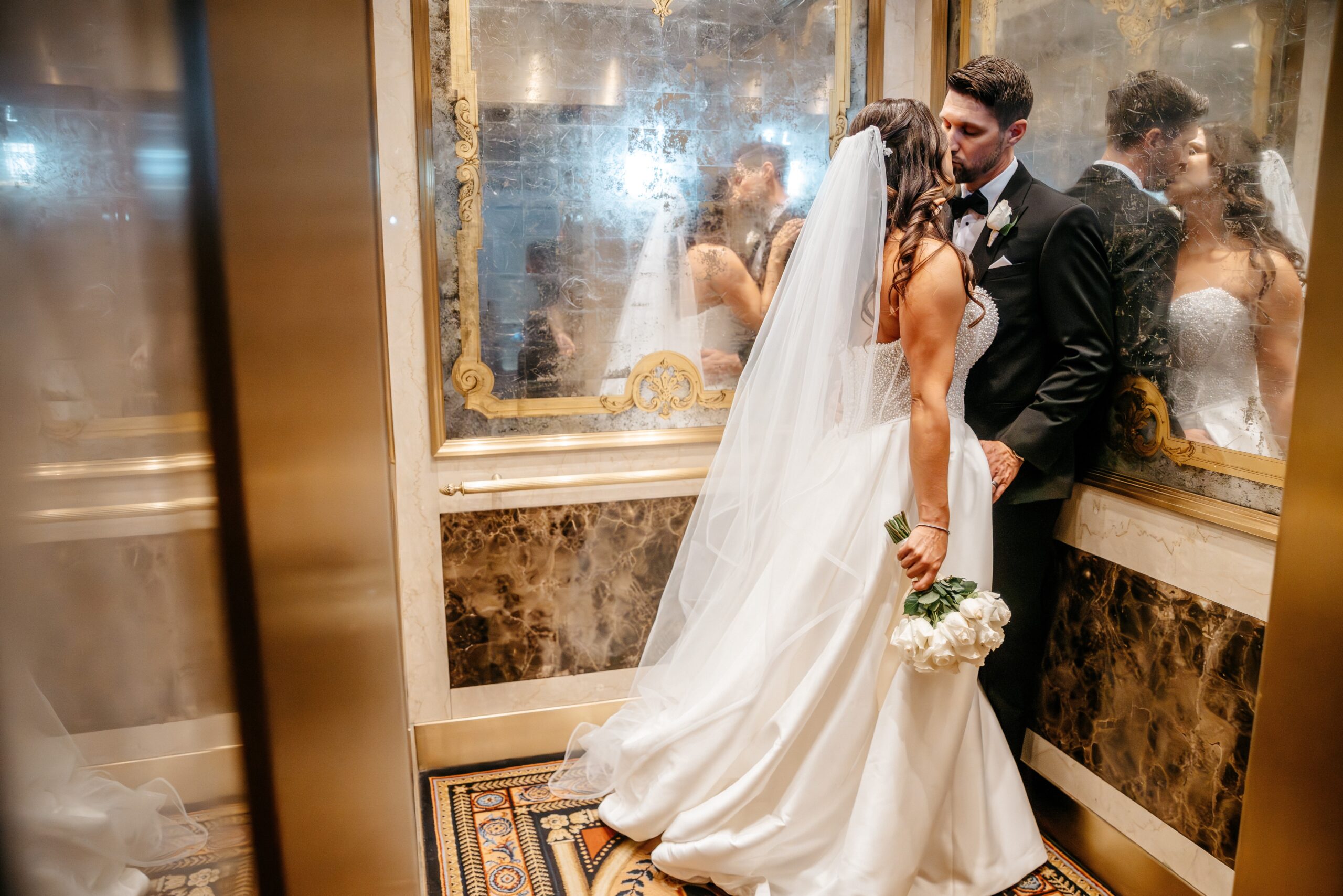 Bride and groom kissing in vintage elevator at Boston hotel wedding venue, romantic indoor wedding moment