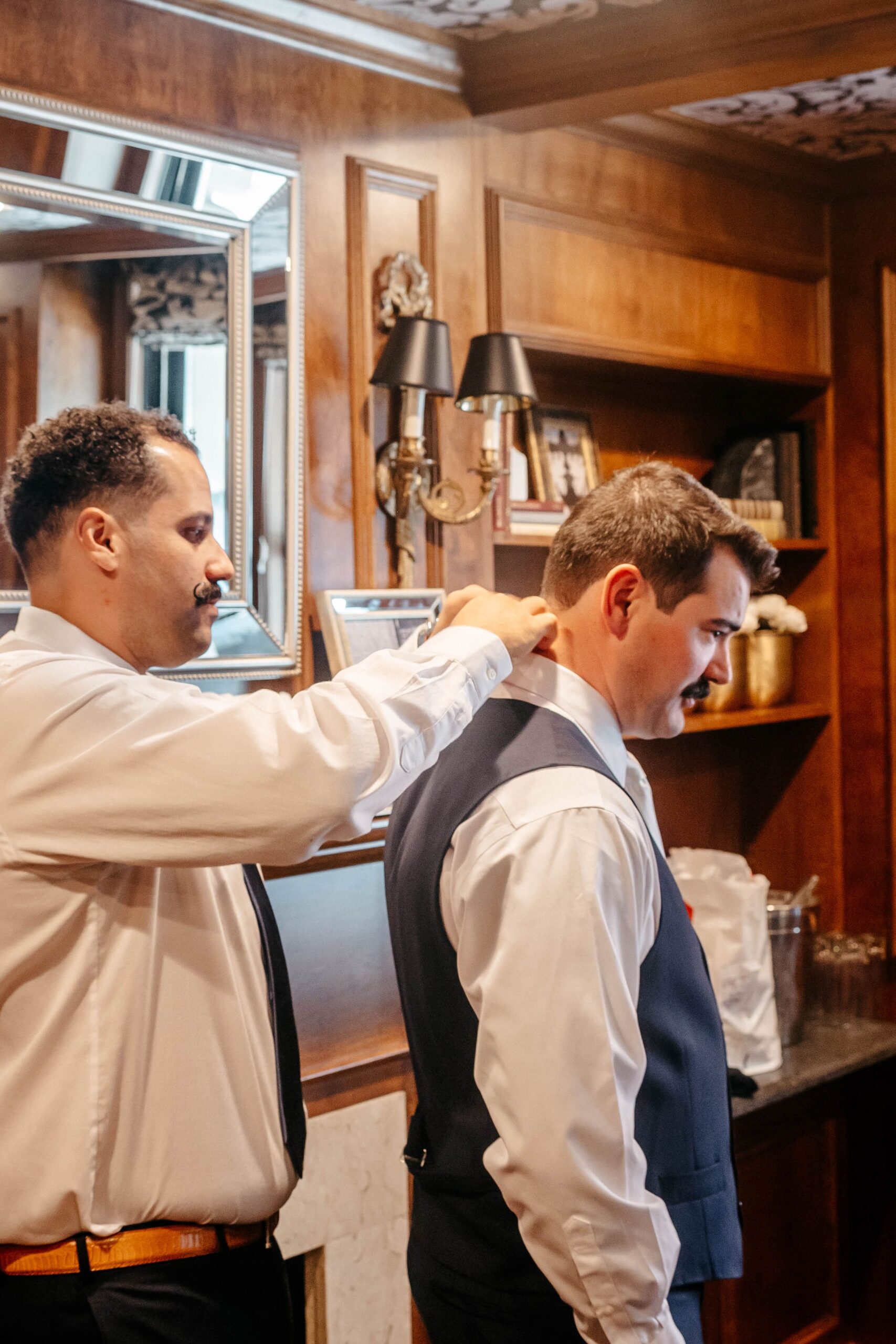 Groom getting ready with groomsman at Boston hotel wedding venue, candid preparation moment indoors