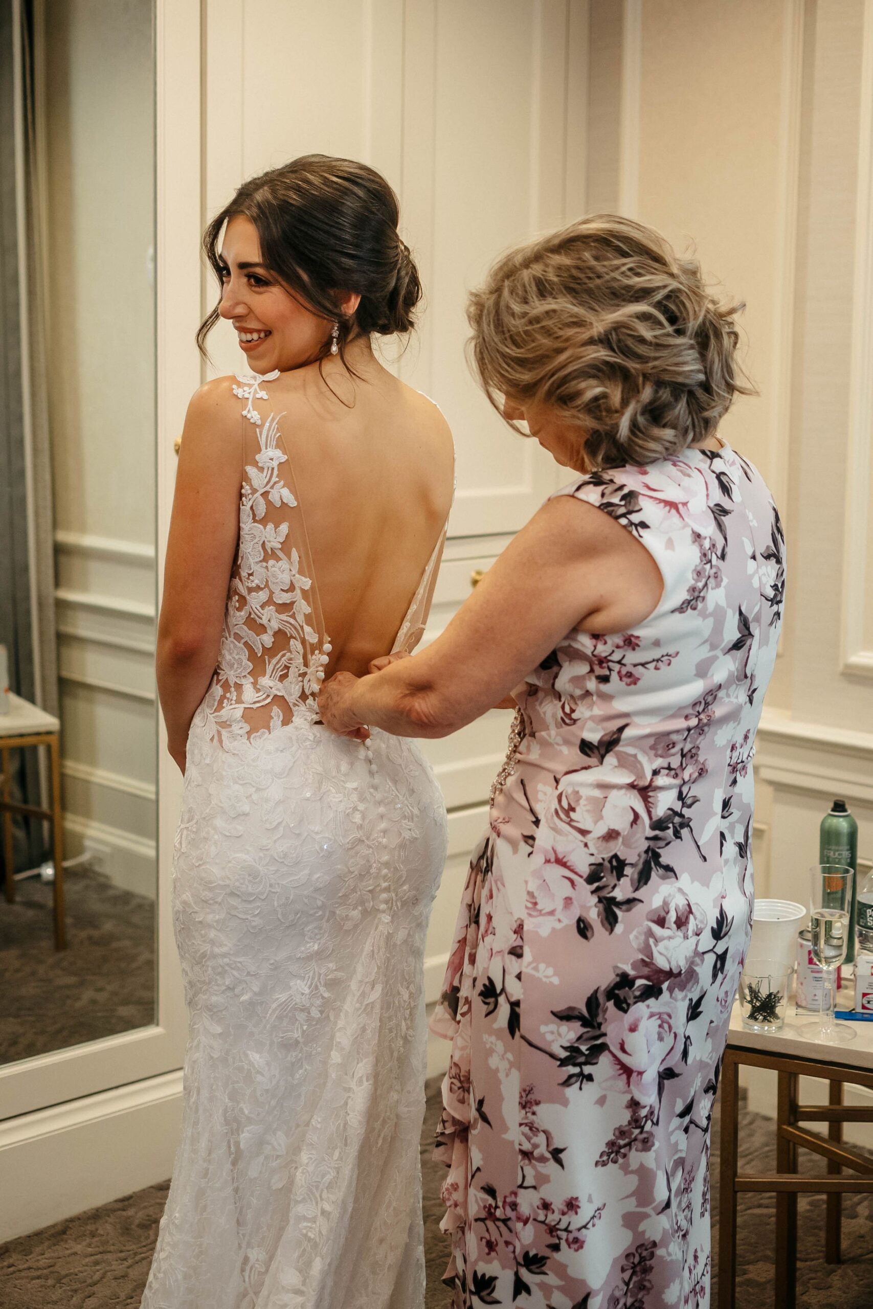 Bride getting into lace wedding dress with help from mother at Boston hotel wedding venue