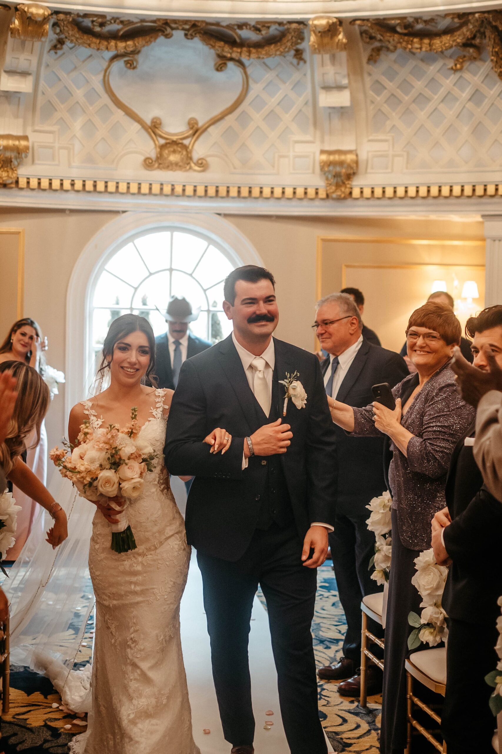 Bride and groom walking down aisle after ceremony at Boston hotel wedding venue surrounded by guests