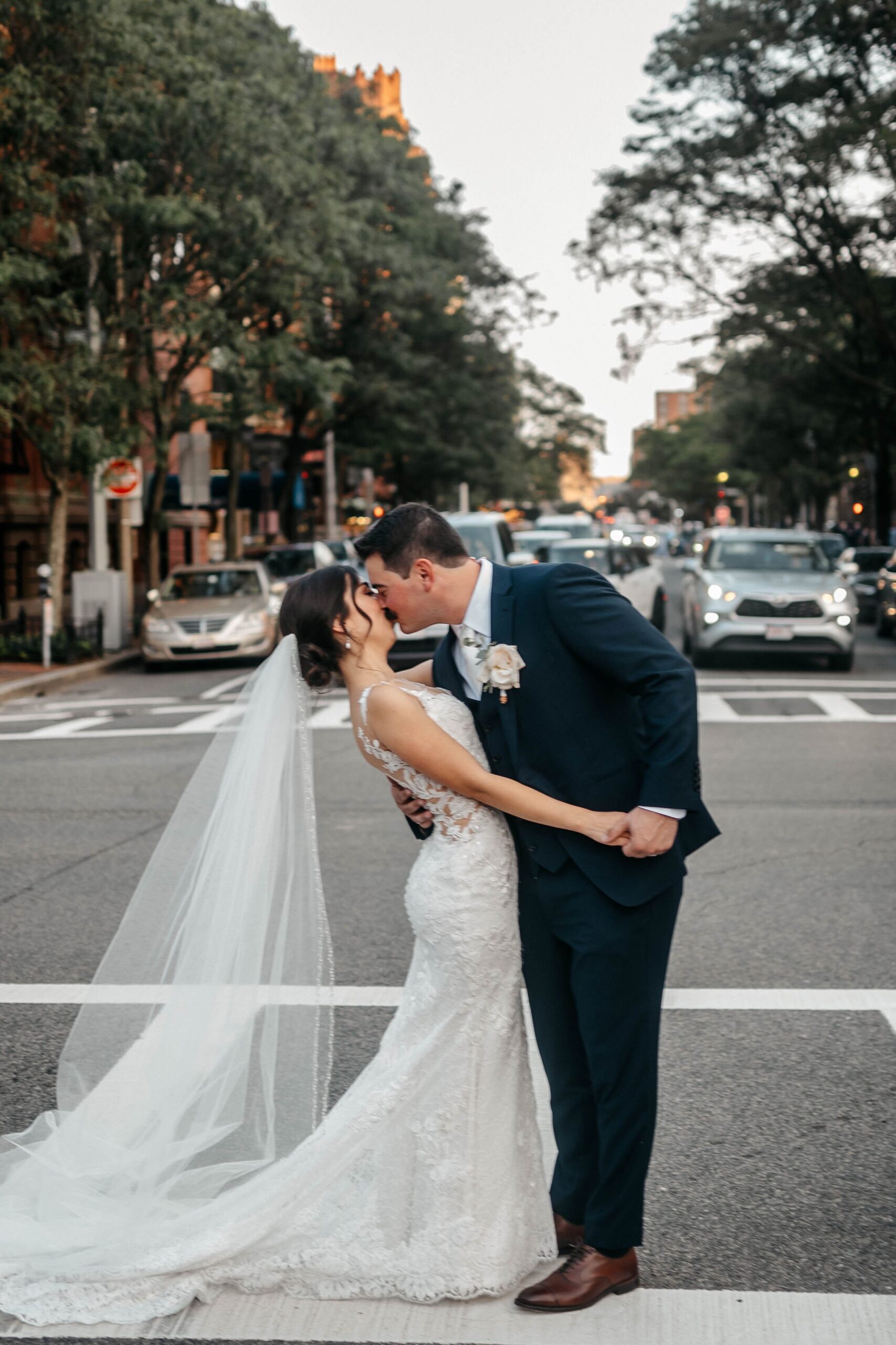 Bride and groom kissing in downtown Boston street near hotel wedding venue, romantic city wedding portrait
