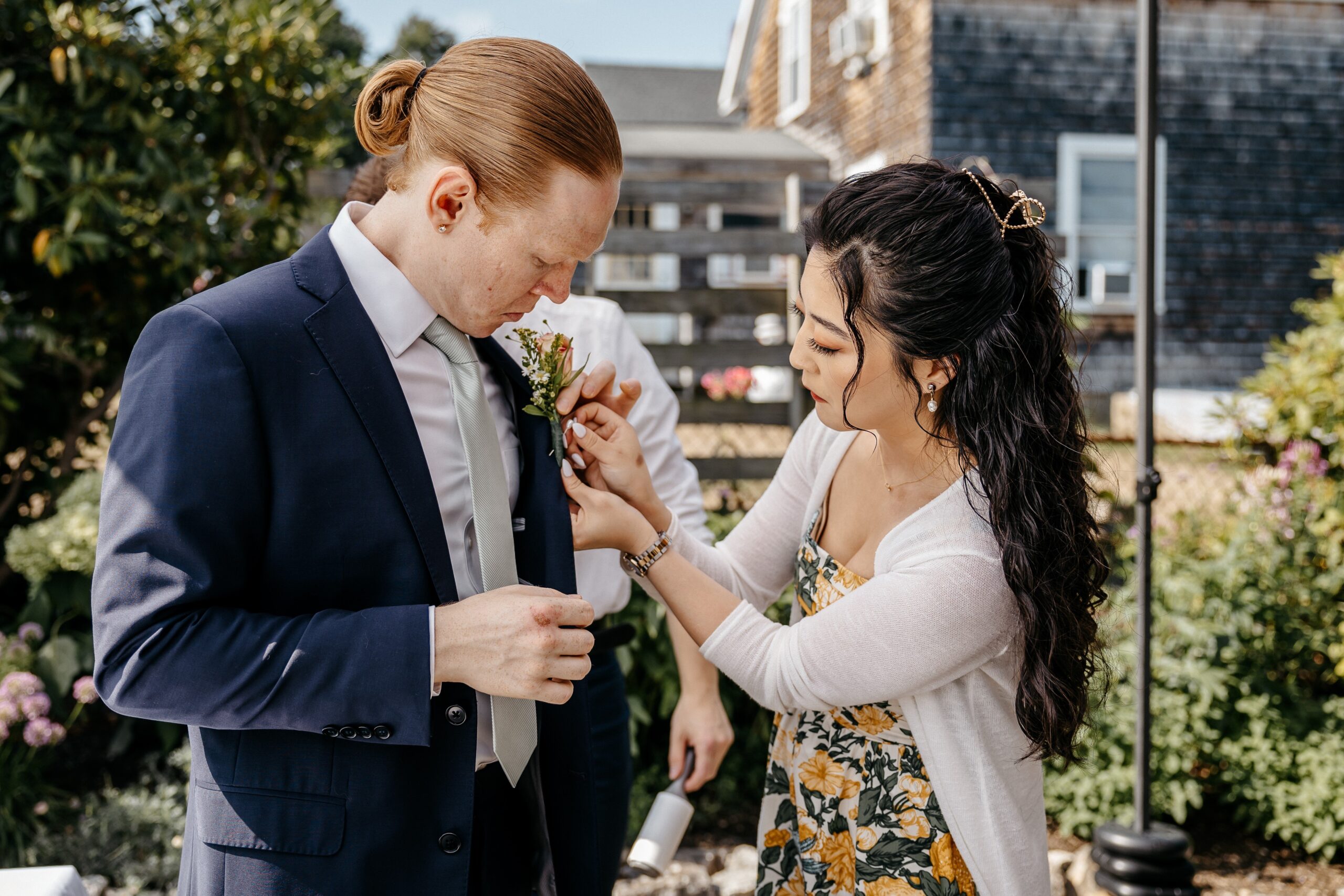 Groom getting boutonniere pinned during Boston wedding planning outdoor getting ready moment