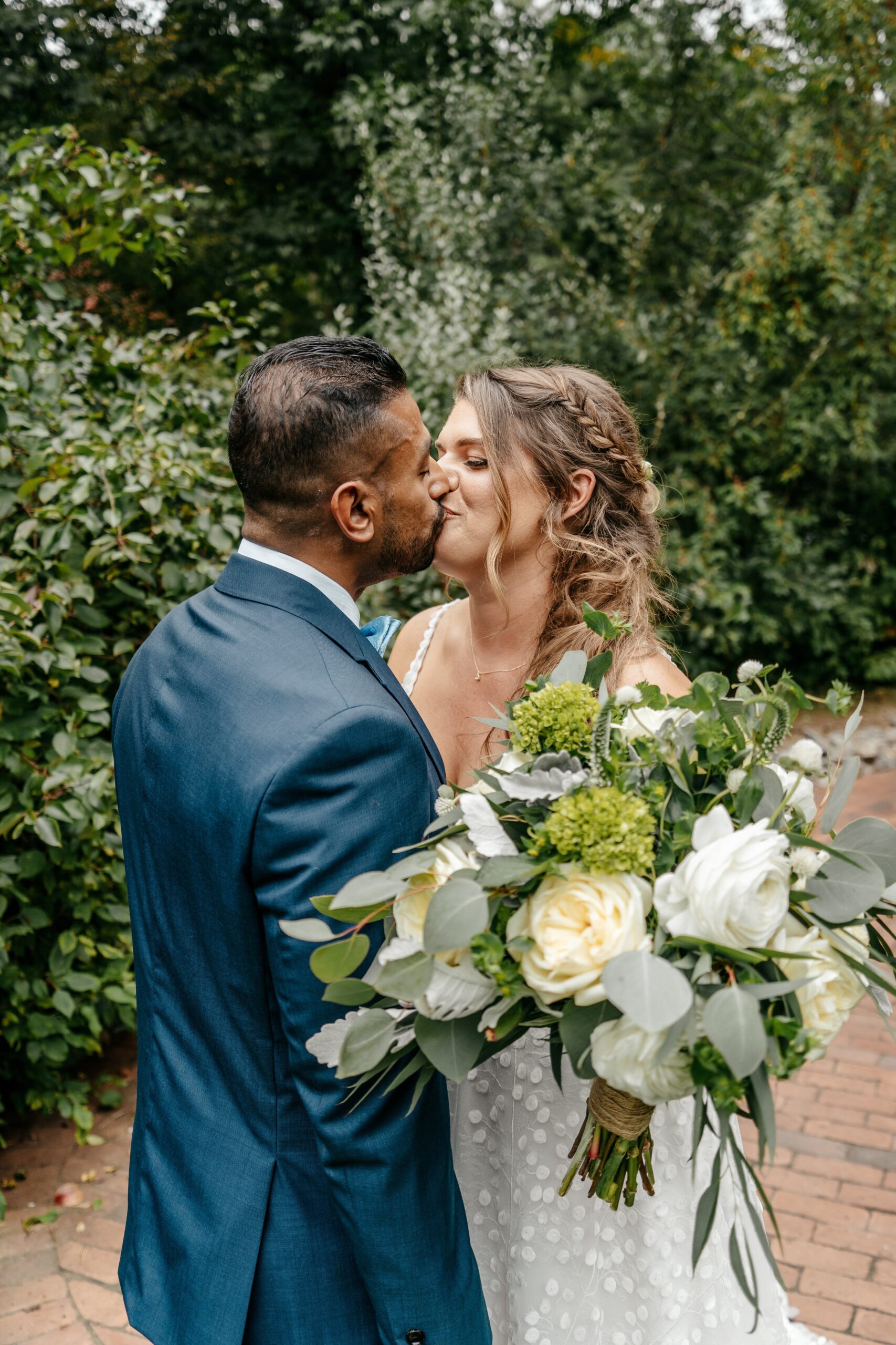 Bride and groom kissing with bouquet during Boston wedding portrait session