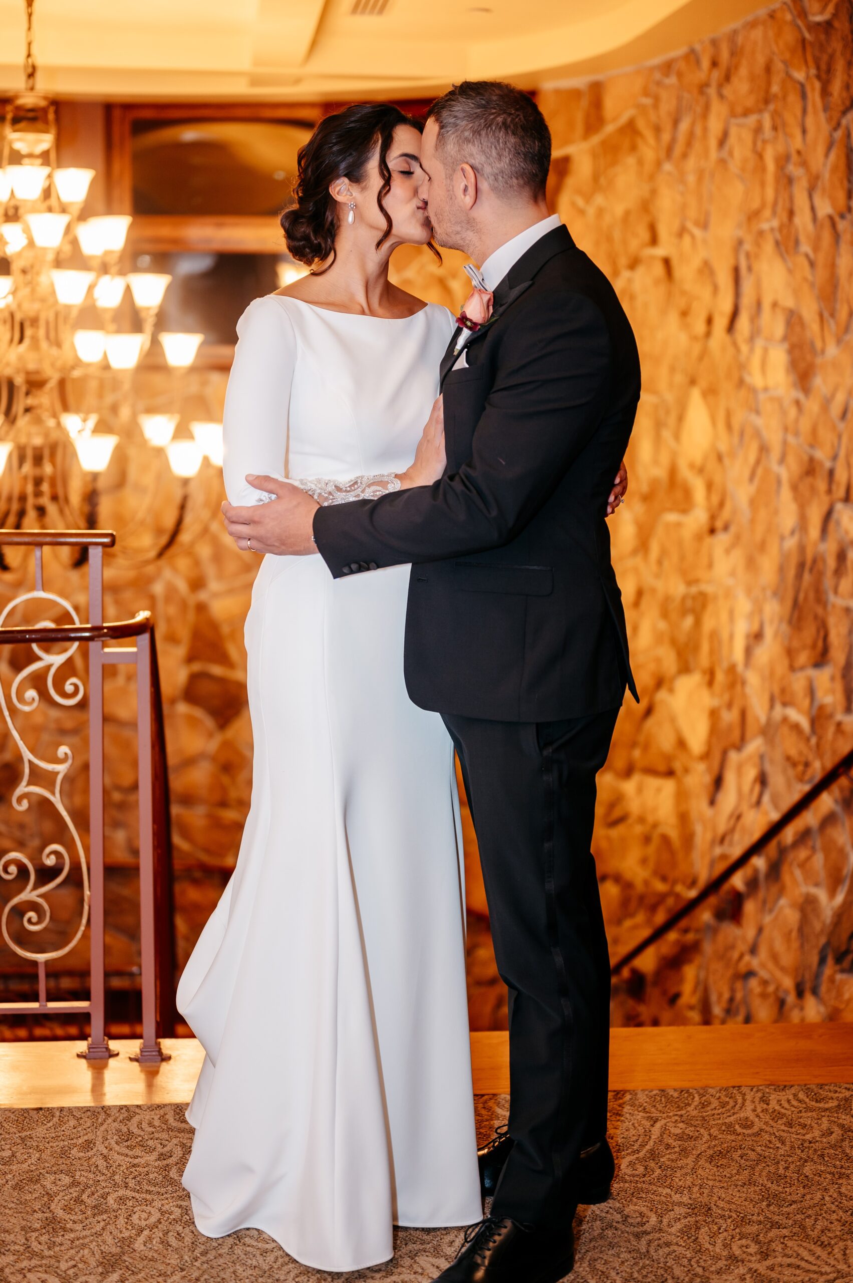 Bride and groom kissing in warm-lit venue during Boston wedding reception