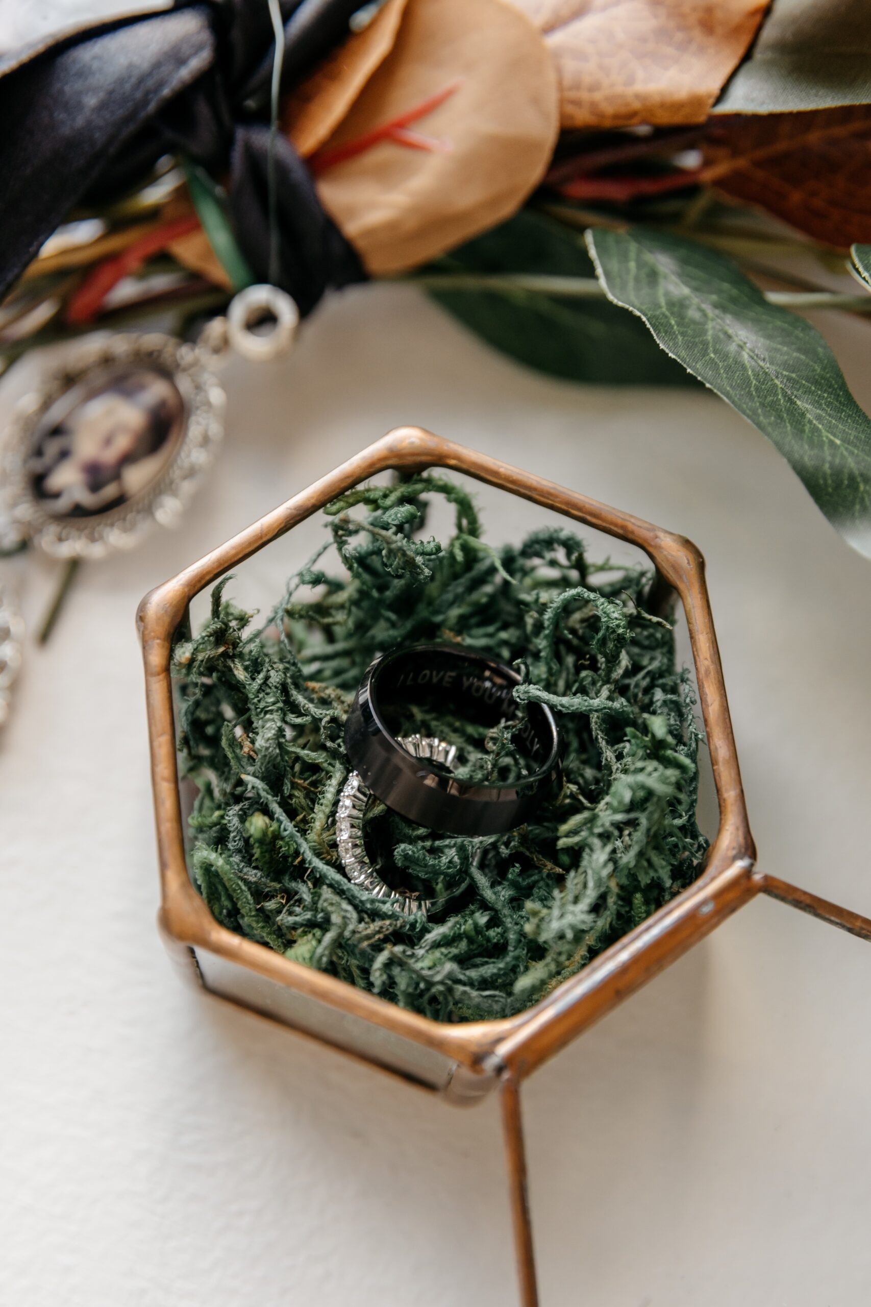 Wedding rings displayed in glass box with greenery during Boston wedding planning detail styling