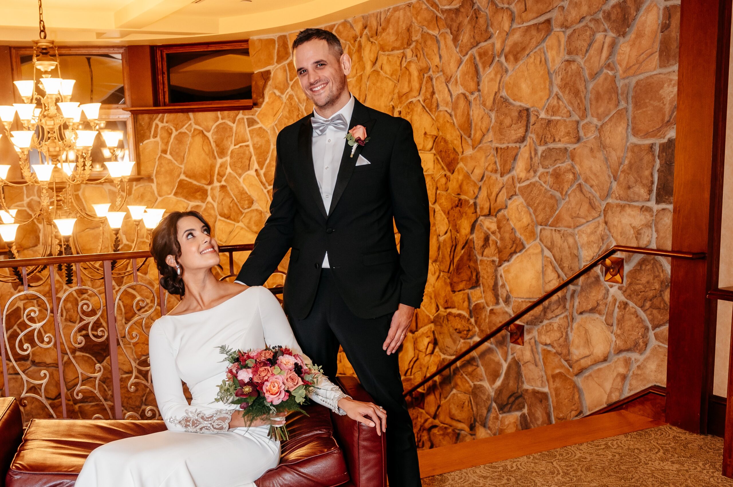 Bride and groom posing on staircase at Cafe Escadrille wedding in Burlington, elegant venue interior with warm lighting