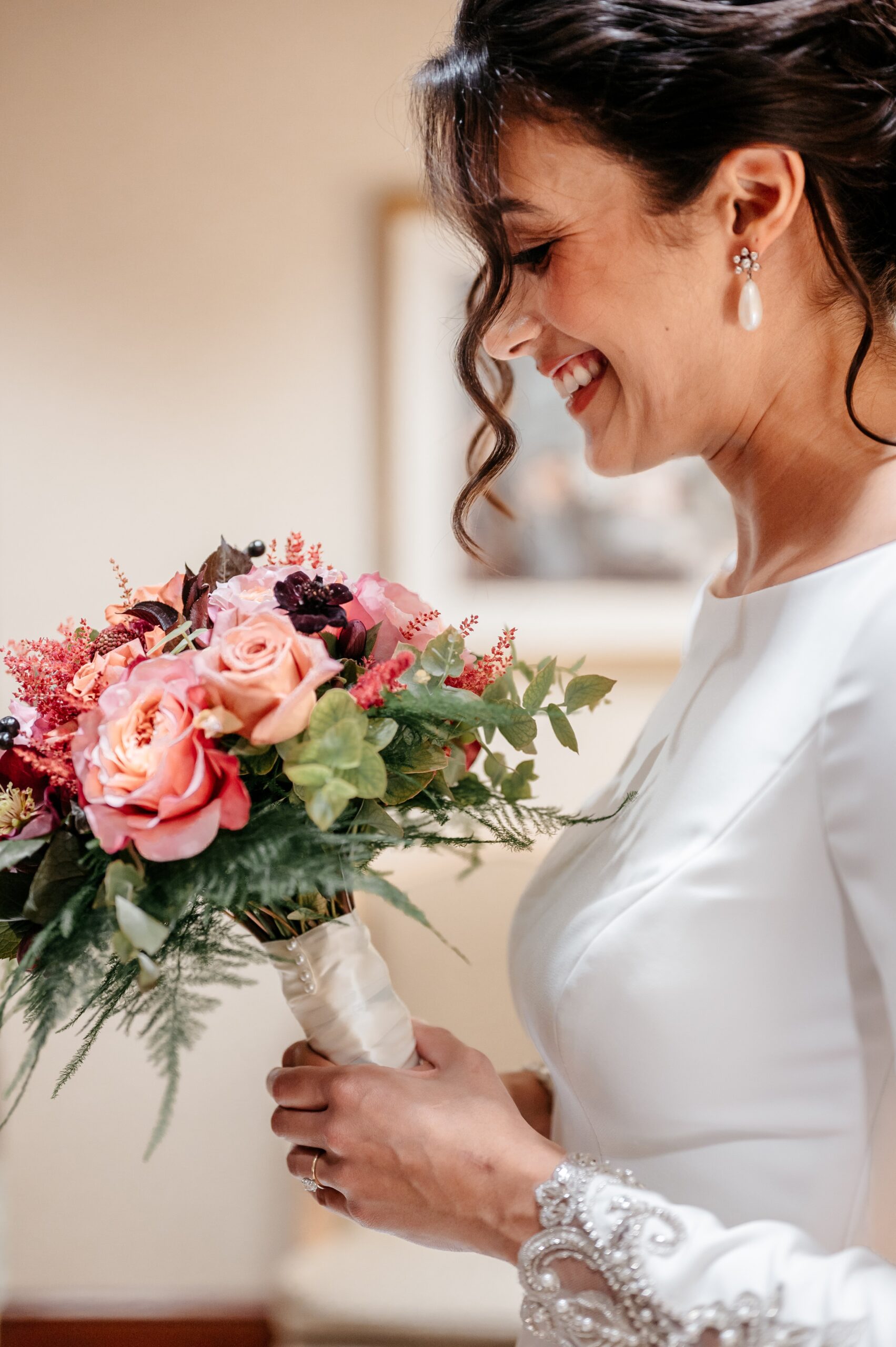 Bride smiling while holding bouquet during Cafe Escadrille wedding in Burlington, soft floral details and elegant bridal style